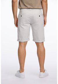 Grå bomullsshorts med uppvikta fållar, bakfickor med knappar, bärs med vita sneakers. Enkelt design, inga mönster eller detaljer.