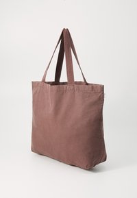 Sac en toile brun avec deux poignées, de forme rectangulaire, texture lisse, sans motifs ni accessoires visibles. Conçu pour une utilisation décontractée.