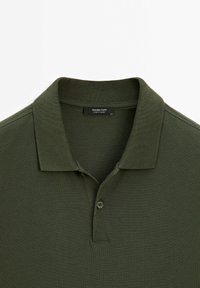 Tmavě zelená polo košile s texturovanou tkaninou, skládacím límcem a dvouknoflíkovou légou. Štítek uvádí "Massimo Dutti, vyrobeno v Turecku."