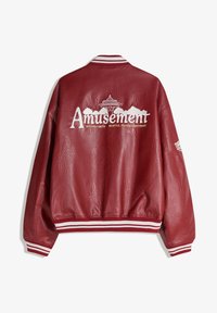 Geacă roșie din piele cu manșete și guler cu dungi albe, cu textul „Amusement” și grafică cu Space Needle din Seattle pe spate.