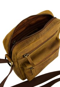 Hnědá kožená crossbody taška s více zipovými přihrádkami, texturovaným povrchem a dlouhým nastavitelným popruhem. Zipy a akcenty v bronzové barvě.
