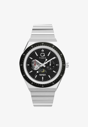 Zegarek Timex Q z kopertą ze stali nierdzewnej, czarną tarczą, logo NASA, wskaźnikami dni i sekund oraz świecącymi wskazówkami i znacznikami.