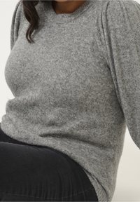 Grauer Pullover aus weichem, strukturiertem Stoff mit rundem Halsausschnitt und puffärmeligen Details, kombiniert mit schwarzen Hosen.