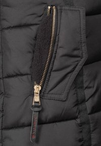 Black puffer jacket fabric with quilted pattern. Features a gold zipper with black fleece lining and a logo tag on the zipper pull.