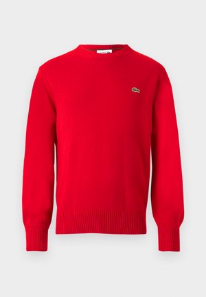 Maglione rosso girocollo realizzato in tessuto a maglia. Presenta polsini e orlo a costine, con un piccolo logo verde sul petto. Design semplice e pulito.