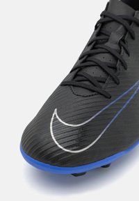 Botín de fútbol negro con parte superior texturizada, presenta un swoosh plateado de Nike y acentos en la suela azul, además de un sistema de cordones integrado para un ajuste óptimo.