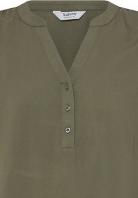 Blouse vert olive avec trois boutons sur une patte de boutonnage en V et un petit col rond. L'étiquette indique « b.young The Collection ».