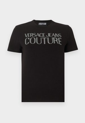 Črna majica s kratkimi rokavi z napisom "VERSACE JEANS COUTURE" iz srebrnih kristalčkov čez prsni del in z oznako znamke na ovratniku.
