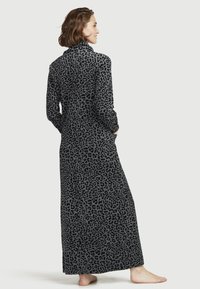 Maxiklänning i mjuk grå fleece med svart leopardmönster; har långa ärmar och sidofickor; avslappnad silhuett och golvlång design.