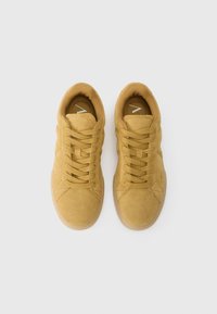Zapatillas de gamuza amarilla con suela de goma, punta redonda y cordones planos, que presentan una textura suave y un diseño minimalista.