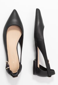 Schwarze Leder-Slingback-Ballerinas mit spitzen Zehen, einem kleinen Absatz und einer seitlichen Schnallenverschluss. Helle beigefarbene Innenauskleidung. Glatte Textur.
