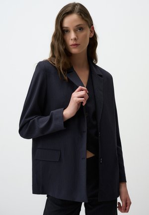 Blazer navy a righe sottili in tessuto leggero, con colletto a punta, chiusura frontale con un bottone singolo e dettagli con tasche laterali.