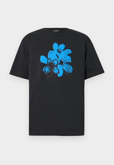 T-shirt en coton noir avec un grand motif abstrait de fleurs bleues avec des accents noirs, manches courtes et col rond.
