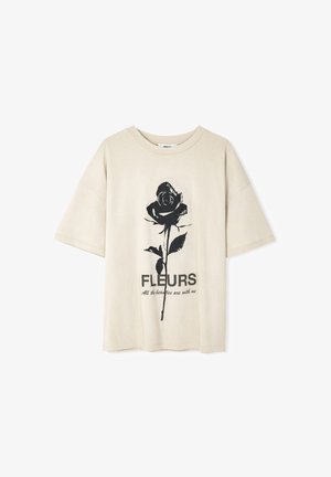 Beige katoenen t-shirt met korte mouwen. Heeft een zwarte roos graphic en de tekst "FLEURS" met daaronder "Alle schoonheden zijn bij ons".