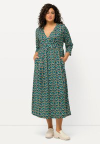Sukienka maxi w kwiatowy wzór w odcieniu teal, ozdobiona pomarańczowymi, różowymi i żółtymi kropkami; dekolt w serek, długie rękawy, pasek w talii i kieszenie po bokach.