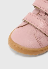 Chaussure en cuir texturé rose avec des bandes Velcro et une semelle en caoutchouc. Présente des détails cousus et un design à bout arrondi.