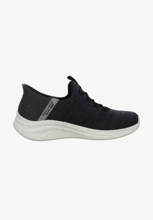 Zwart-grijze stoffen sneaker met een gestructureerd bovenwerk, elastische veters en een witte zool met spikkels. Heeft een gelabeld zijaccent.