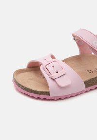 Rosa sandaler laget av syntetisk materiale med en korkfotbed, med en spenne og en teksturert såle med bølget kant.