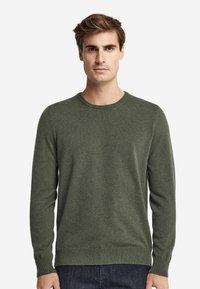 Mörkgrön tröja, rund halsringning, långa ärmar, stickad textur, ribbade muddar och fåll. Matchas med mörka jeans.