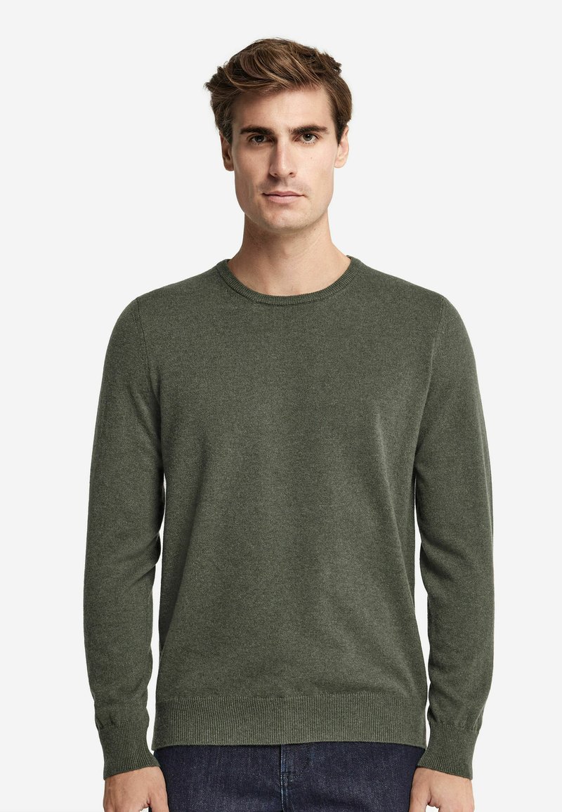 Mörkgrön tröja, rund halsringning, långa ärmar, stickad textur, ribbade muddar och fåll. Matchas med mörka jeans.