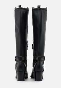 Bottes noires montant jusqu'au genou en cuir lisse avec un talon épais, dotées de fermetures éclair latérales et de lanières décoratives avec des accents de logo.