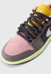 Grijze sneakers met roze en gele accenten, voorzien van een geperforeerde neus, getextureerd suede materiaal en zwarte veters. Neon groene zooldetails.