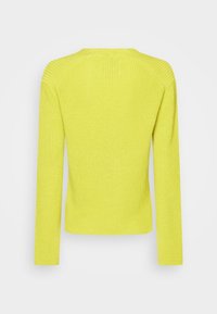 Pull en tricot jaune vif, avec manches longues et encolure arrondie. Tissu texturé avec un motif côtelé. Vue de dos.