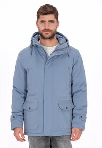 Chaqueta exterior azul claro con capucha, cierre frontal con cremallera, dos bolsillos en el pecho y detalles con botones de presión. Presenta una textura suave.