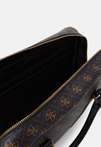 Braune Handtasche mit Muster und goldenen Beschlägen, ausgestattet mit einem Reißverschluss und einem schwarzen Innenfutter. Enthält eine interne Tasche.