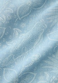 Tejido azul claro con un patrón de flores y peces en blanco. La textura parece suave con un ligero brillo, mostrando diseños detallados.