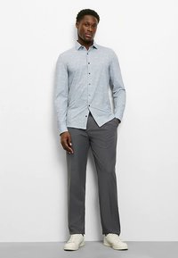 Hellblaues langärmeliges Hemd mit Paisley-Muster, kombiniert mit grauen Hosen und weißen Turnschuhen, in schlanker Passform und mit Knopfleiste.