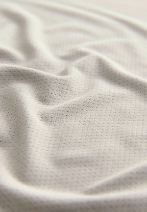 Tessuto beige chiaro con un motivo a punti testurizzato. Texture morbida e liscia con pieghe delicate e drappeggi. Ideale per diverse applicazioni tessili.