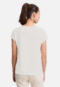 T-shirt blanc à manches courtes, en matériau doux, col rond, coupe décontractée. Vue arrière montrant une texture lisse et des détails de design simples.