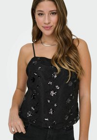 Czarny top na ramiączkach z koronkową nakładką i cekinowymi wzorami kwiatowymi. Posiada cienkie ramiączka i luźny krój. Gładka faktura z delikatnym połyskiem.
