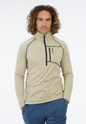 Bežový fleece pulóver s vysokým golierom, polozipsom vpredu, čiernymi akcentmi a vreckom na hrudi. Má textúrovanú tkaninu a priliehavé rukávy.