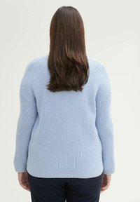 Jasnoniebieski sweter o teksturowanym prążkowanym wzorze, z długimi rękawami i luźnym krojem. Hem jest lekko dłuższy z tyłu.