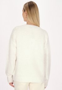 Witte, fluffy sweater met een relaxed fit, verlaagde schouders en geribbelde manchetten. Zachte textuur en minimale naden. Achteraanzicht weergegeven.