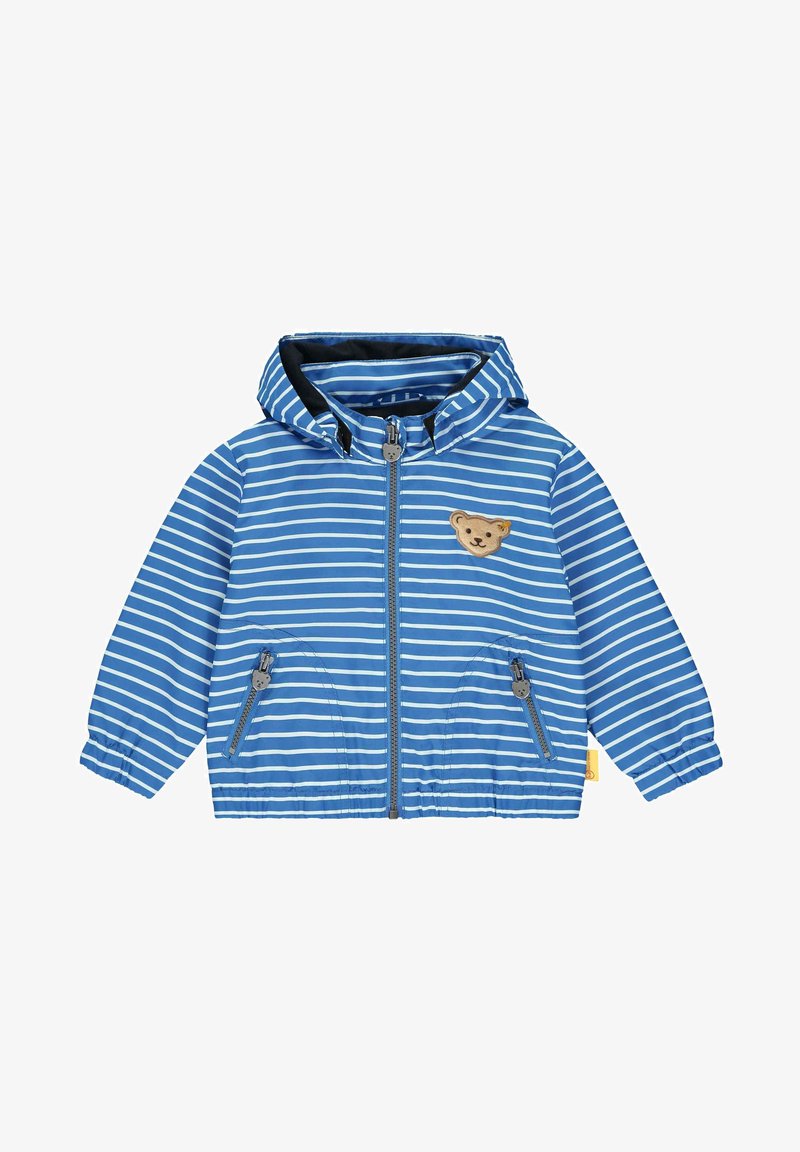 Veste légère bleue à rayures avec capuche. Comprend une fermeture éclair, deux poches latérales et un écusson ours sur la poitrine. Texture lisse.