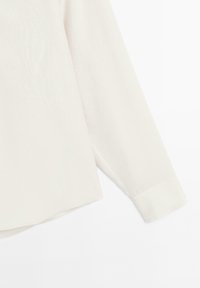 Long-sleeve blouse in soft white fabric, featuring a smooth texture, a loose fit, and a straight hem with a buttoned cuff detail.