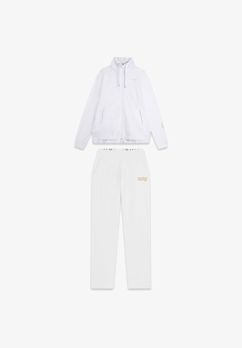 Chándal deportivo blanco que presenta una chaqueta con cremallera y un cuello alto, junto con pantalones a juego. Acentos dorados y logotipo en ambas piezas. Textura suave.