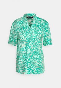 Polo à manches courtes de couleur verte avec un imprimé zèbre blanc. Il présente un col et un devant à boutons. Tissu lisse et léger.