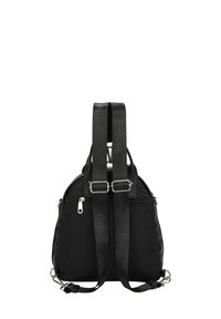 Mochila de tela negra con correas ajustables, herrajes plateados y detalles de logo. Presenta una forma redondeada y un bolsillo con cremallera en el lateral.