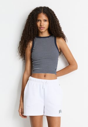 Bandeau atasan bergaris navy dan putih dengan leher bundar. Dipadukan dengan celana pendek berpinggang elastis putih yang menampilkan detail teks hijau.