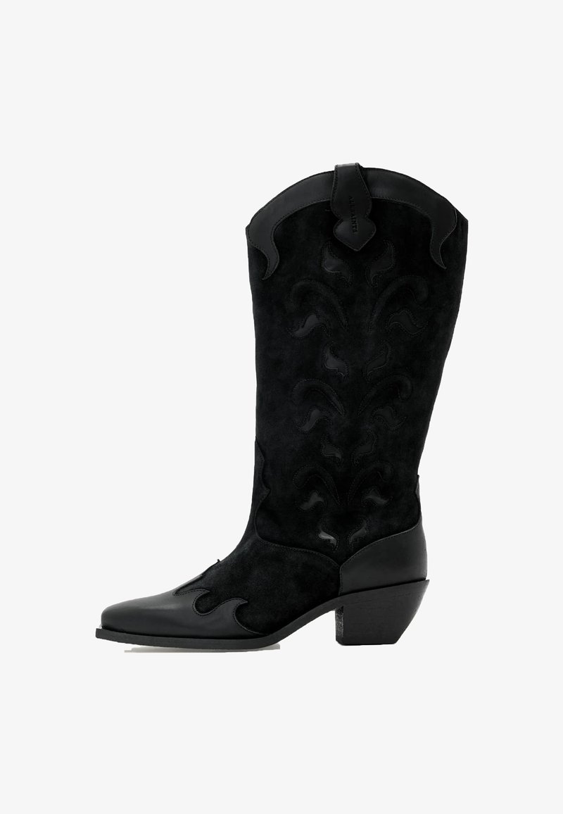 Musta mokkainen cowboy-saapas, jossa on nahkainen korko. Sisältää monimutkaisia sävyisiä kuvioita ja leveän, terävän kärjen. Neliönmuotoinen korkki.