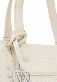 Borsa strutturata color beige chiaro realizzata in pelle testurizzata. Presenta un charm con logo argentato e manici cuciti per un tocco in più.