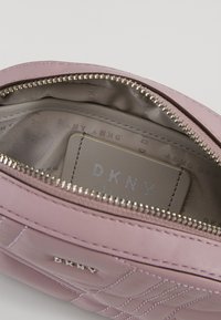 Pink quilted leather bag interior with gray lining and a stitched tag displaying “DKNY.” Features a silver zipper and minimalist design.