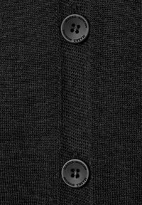 Schwarze Strickjacke mit zwei großen schwarzen Knöpfen, aus strukturiertem Stoff mit sichtbaren Nähten im Knopfbereich.