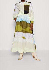 Pitkä, napitettava mekko pastelliväripaletilla, jossa vihreän, sinisen ja beigen sävyisiä aaltoja. Kuminauhavyötärö ja pitkät hihat.