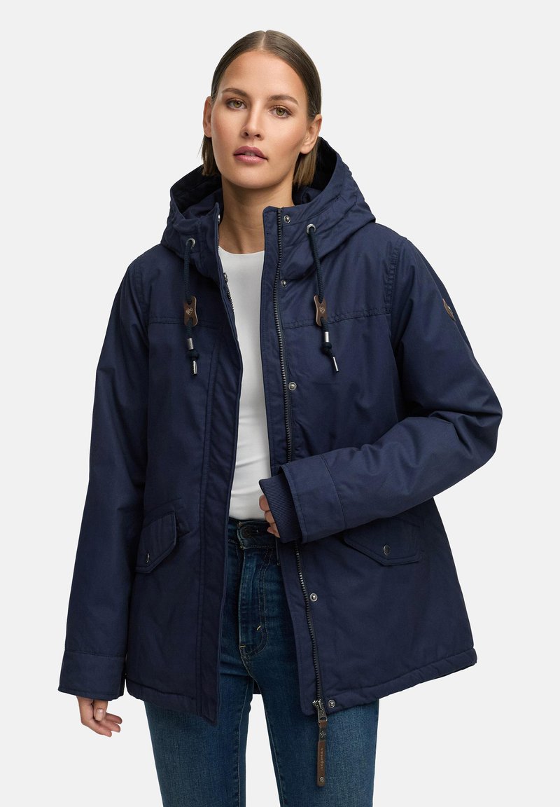 Mörkblå utomhusjacka med huva, dragsko och dragkedja framtill. Har sidofickor och ribbade muddar. Vattentätt tyg.