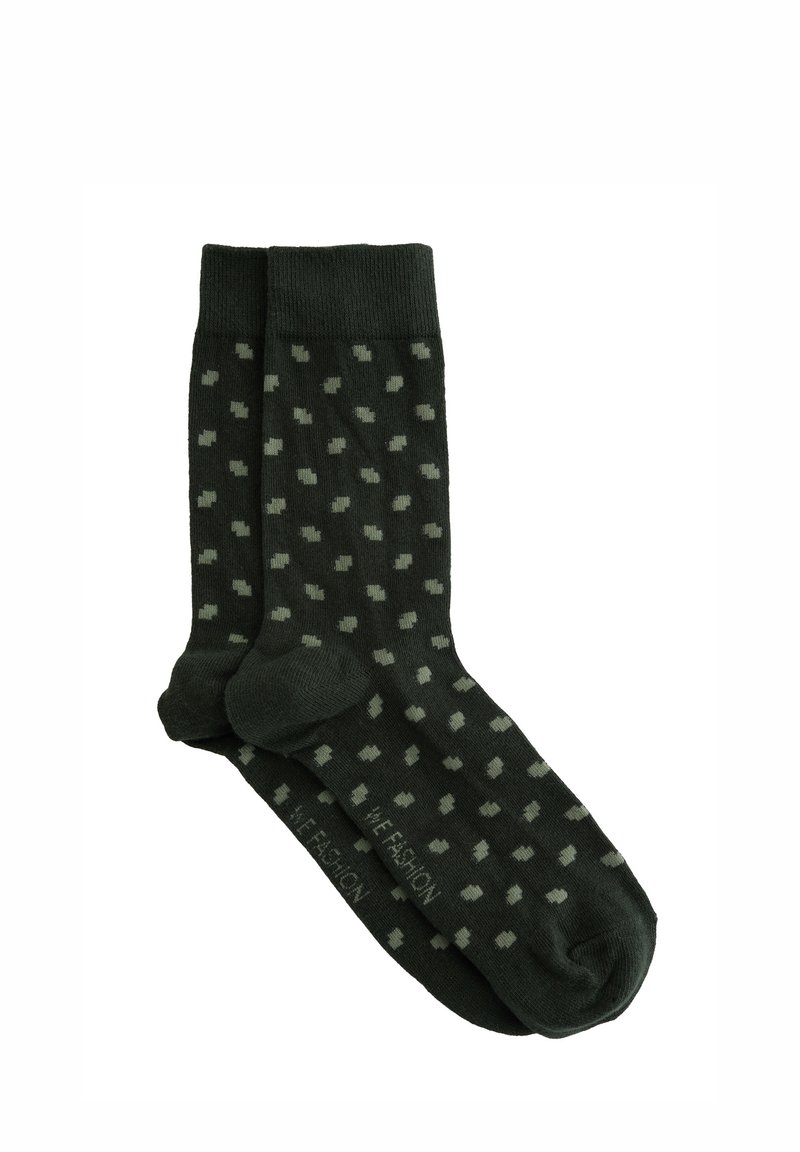 Temnozeleni nogavice z vzorcem pik v svetlejši zeleni. Narejene so iz bombaža, z rebrastimi manšetami in enotno barvo na prstnih in petnih delih.